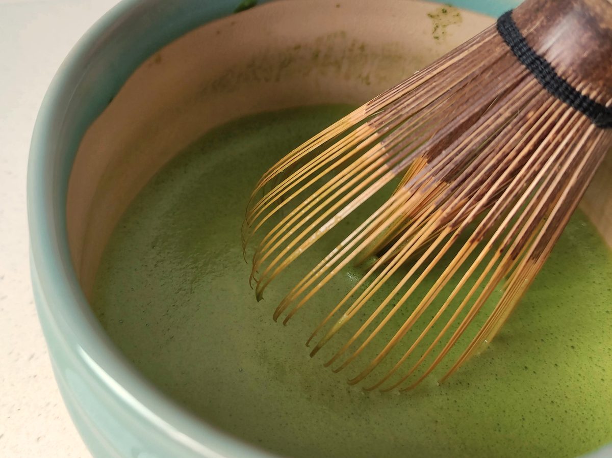 Matcha being whisked with a traditional chasen